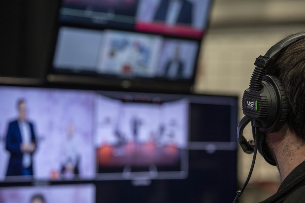 Technician wearing communications headset in front of a bank of video monitors